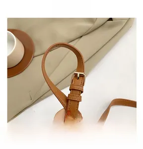 Detail of adjustable brown leather shoulder strap with high-quality gold metal buckle