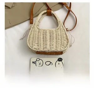 Detail of beige straw woven bucket bag with brown leather handles and drawstring liner
