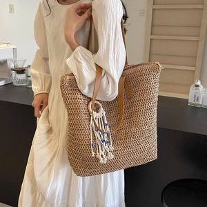 Fashionable woven straw tote bag with brown leather straps and tassel pendant for women