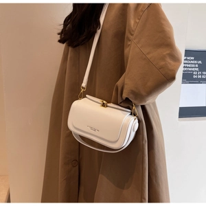 Detail of white crossbody bag with gold twist lock and adjustable shoulder straps