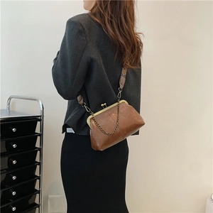 Vintage brown leather frame handbag with ethnic strap and chain on model shoulder