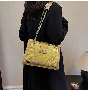 Detailansicht der luxuriösen goldenen Schultertasche mit Krokoprägung und Metalldrehverschluss