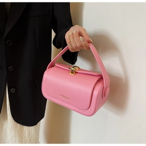 Detail of pink cylindrical leather handbag with gold shell lock and fashion text