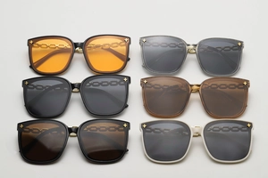 Détail de lunettes de soleil carrées avec rivets étoile dorés et branches à maillons