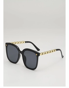 Détail de lunettes de soleil carrées avec branches chaîne dorée et rivets étoiles noirs