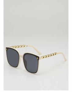 Détail de lunettes de soleil oversize avec monture crème et branches en chaîne dorée
