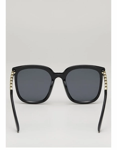 Détail de lunettes de soleil carrées avec monture noire brillante et perles dorées