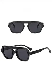Détail de lunettes pilote noires avec texture nervurée et verres teintés gris