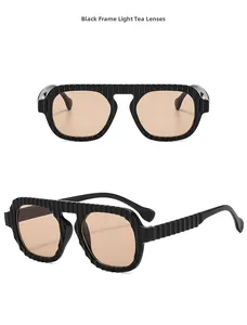 Détail de lunettes pilote avec monture noire, verres thé clair et branches texturées