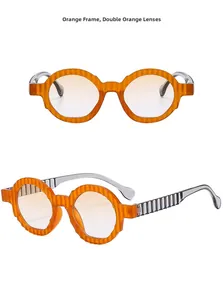 Detail view of orange oversized sunglasses featuring scalloped wavy frames and gradient lenses