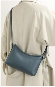 Close-up of navy blue lychee textured leather shoulder bag on a beige trench coat
