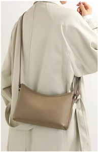 Close-up of brown litchi pattern leather shoulder bag on a model wearing a beige coat