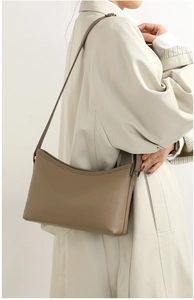 Detailed texture of brown lychee grain leather shoulder bag worn with a white coat