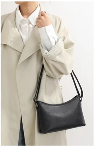 Classic black litchi texture shoulder bag worn with a stylish trench coat for women