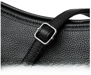 Macro view of adjustable silver metal buckle and litchi grain texture on black shoulder bag