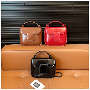 Detailed arrangement of three glossy rectangular crossbody bags on a leather bench