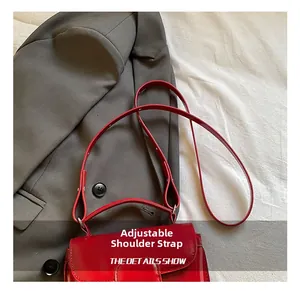 Detail of red oil wax leather handbag showing the adjustable strap on fabric background