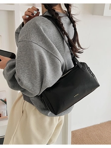 Close-up of black leather pillow bag featuring pebble texture and gold metal logo