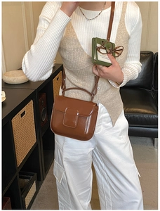 Detail of brown wax leather crossbody bag with flap cover and long shoulder strap