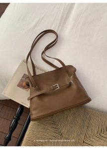 Detalle del bolso de hombro en cuero mate marrón con hebilla plateada y correas dobles