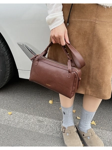 Close-up of brown leather boston bag with gold lettering and sleek zipper closure
