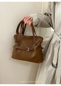 Detalle de bolso tote marrón minimalista con hebilla retro y textura de cuero premium