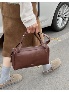 Detail of dark brown leather Boston bag with gold LILLU lettering and top handle