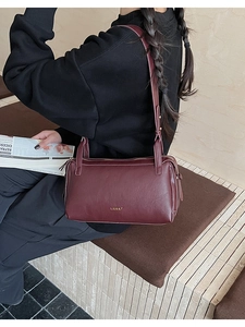 Detail of dark red leather pillow bag featuring gold LILLIU logo and adjustable strap