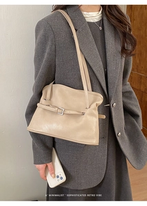Detalle de un bolso tote de cuero beige con hebilla en una modelo con blazer gris