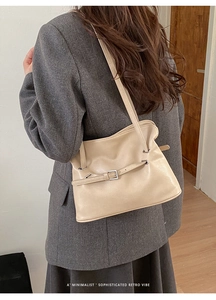 Vista detallada de bolso tote beige plisado combinado con una chaqueta de traje gris
