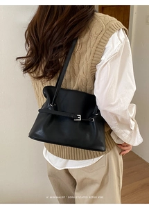 Vista posterior del bolso tote de cuero negro minimalista con hebilla plateada puesto