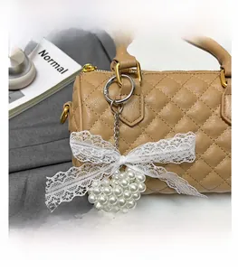 Close-up of khaki quilted Boston bag with pearl heart charm and lace bow details