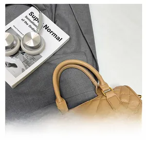 Detail of comfortable round handle on khaki quilted leather boston bag with gold hardware