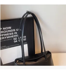 Close-up of black PU leather shoulder bag featuring adjustable long handles and matte finish