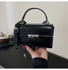 Détail du sac à main noir verni avec fermoir rotatif argenté et bandoulière réglable