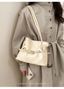 Detalle de bolso tote crema plisado con hebilla metálica fina y correas dobles elegantes
