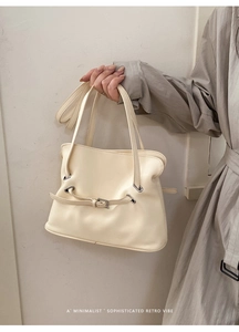 Detalle del bolso tote crema plisado con ojales plateados y diseño de correa minimalista