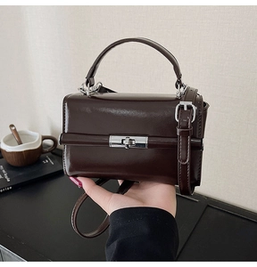 Détail d'un sac à main marron brillant avec fermoir argenté et bandoulière réglable