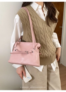 Detalle de bolso tote retro rosa con hebilla en una modelo con jersey beige