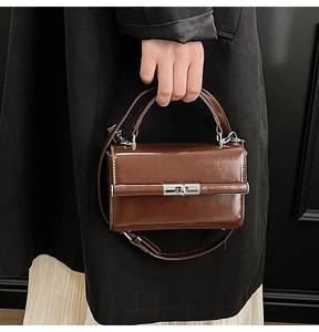Détail d'un sac à main vintage marron en cuir brillant avec fermoir rotatif argenté