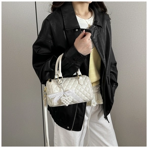 White quilted cylinder bag with pearl heart charm and lace bow shown on a model