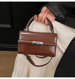 Détail d'un sac à main marron en cuir avec fermoir rotatif argenté et bandoulière