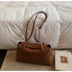 Detail of caramel brown PU leather handbag featuring a flap closure and slim shoulder straps