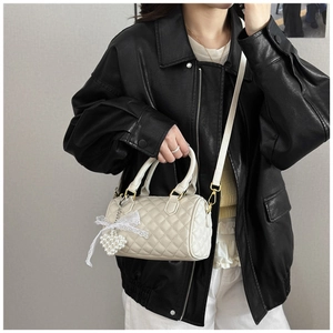 Close-up of quilted cream Boston bag with pearl heart charm and lace bow detail