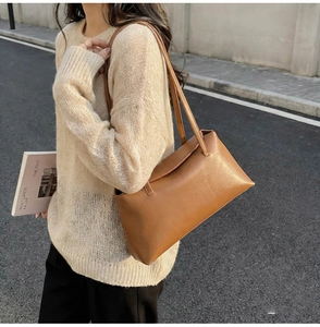 Outdoor street view of a dark brown minimalist PU leather shoulder bag with flap closure
