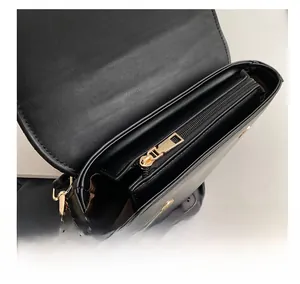 Detail shot of black matte leather shoulder bag with gold zipper and brown lining