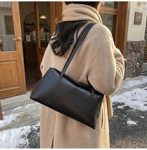 Minimalist black PU leather shoulder bag styled with a winter coat in a cafe outdoor setting