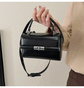 Détail du sac à main noir brillant avec fermoir tournant argenté et bandoulière chaîne