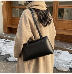 Detail of a black leather shoulder bag with thin straps and minimalist design for commute