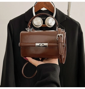 Détail d'un sac boîte vintage marron foncé avec fermoir argenté et texture en cuir